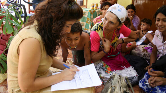 Zwei Frauen und mehrere Kinder füllen ein Dokument aus