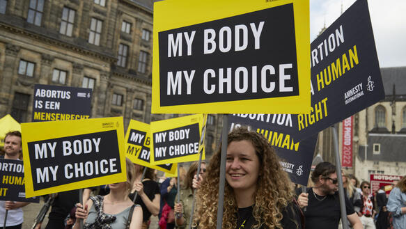 Das Bild zeigt mehrere Demonstrierende auf der Straße mit Schildern wie "My Body My Choice"